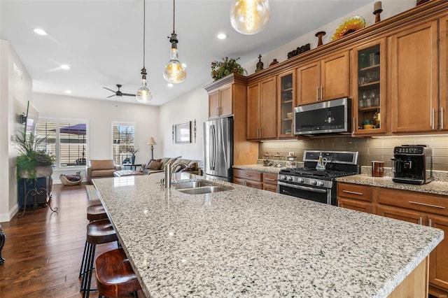 kitchen featuring tasteful backsplash, brown cabinets, appliances with stainless steel finishes, and a sink