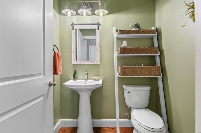 bathroom featuring toilet, baseboards, and a sink