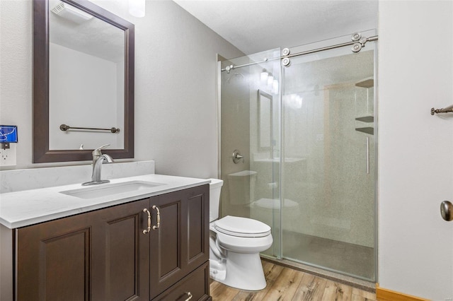 full bath with a stall shower, toilet, vanity, and wood finished floors