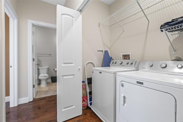 clothes washing area featuring dark wood-style floors, baseboards, and washing machine and dryer