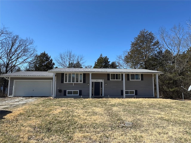 split foyer home with a front lawn, a garage, driveway, and metal roof