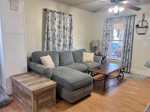 living room featuring baseboards, a ceiling fan, crown molding, and light wood-style floors