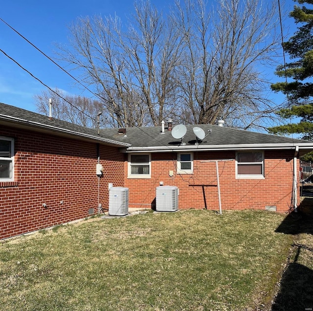 back of property with central air condition unit, brick siding, and a lawn