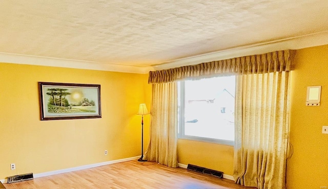 unfurnished room with visible vents, baseboards, a textured ceiling, and wood finished floors