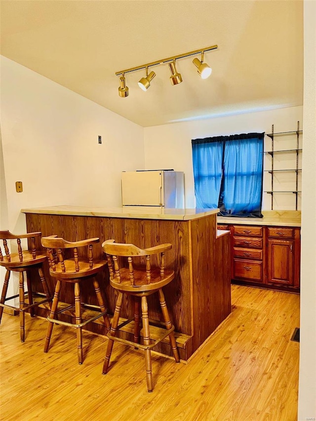 bar featuring a dry bar, freestanding refrigerator, and light wood-style floors