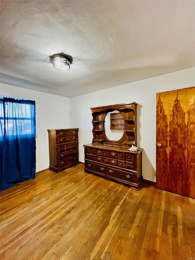 bedroom with a textured ceiling and wood finished floors