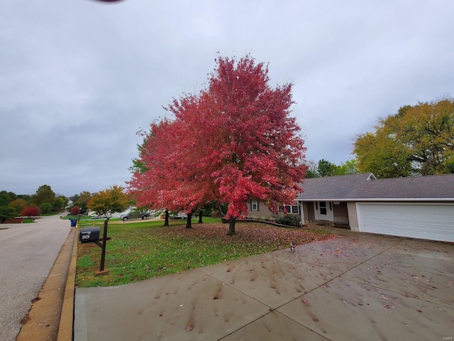 view of front of property with a front lawn, an attached garage, and driveway