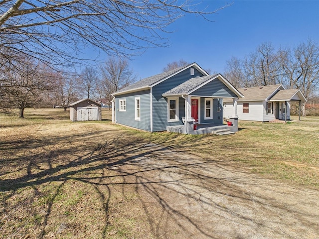 bungalow-style home featuring an outbuilding, a shed, covered porch, a front lawn, and a garage