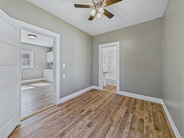 empty room with baseboards, wood finished floors, and a ceiling fan