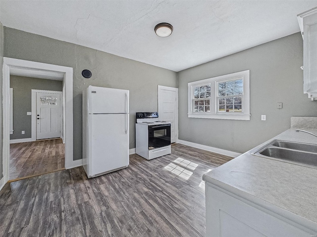 kitchen with electric range, a sink, freestanding refrigerator, baseboards, and dark wood-style flooring