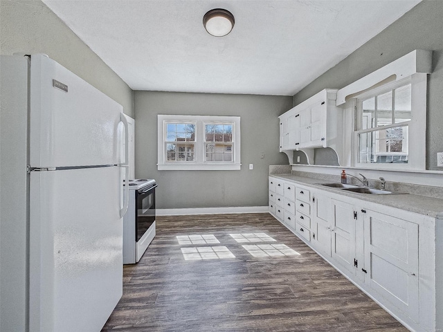 kitchen featuring dark wood finished floors, range with electric stovetop, freestanding refrigerator, white cabinetry, and a sink