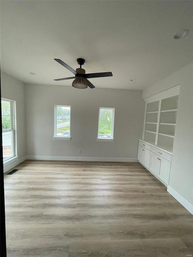 empty room featuring baseboards, wood finished floors, visible vents, and plenty of natural light