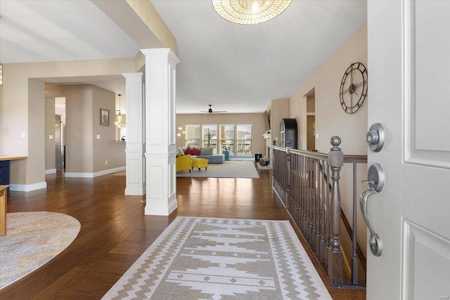 foyer featuring dark wood finished floors, a ceiling fan, baseboards, and decorative columns