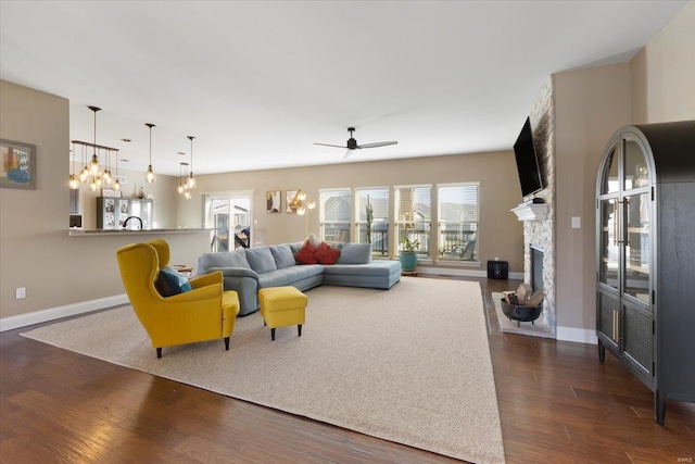 living room featuring ceiling fan, a fireplace, dark wood-type flooring, and baseboards