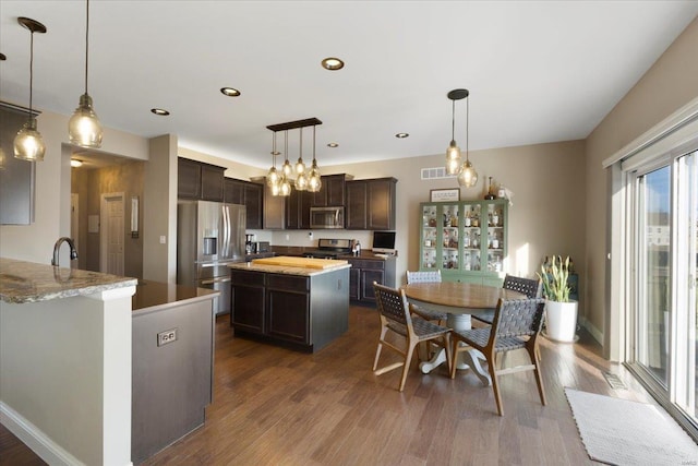 kitchen featuring a sink, dark brown cabinets, dark wood-style flooring, and stainless steel appliances