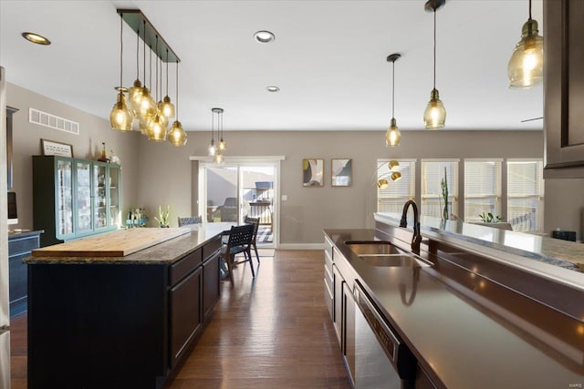 kitchen featuring visible vents, a sink, pendant lighting, stainless steel dishwasher, and dark wood-style flooring