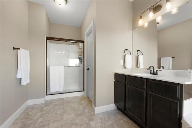 full bathroom with baseboards, a stall shower, and vanity