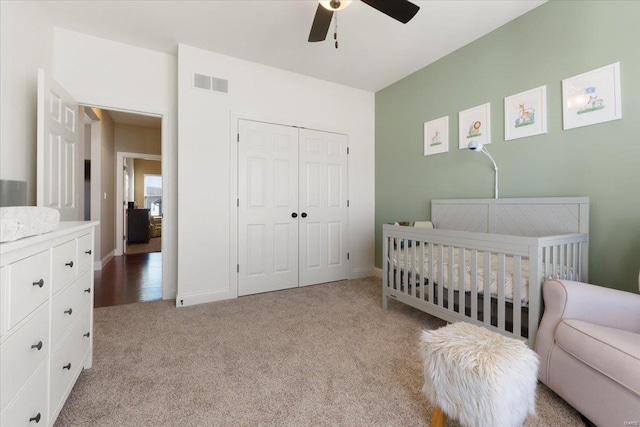 bedroom with baseboards, visible vents, a nursery area, a closet, and light carpet