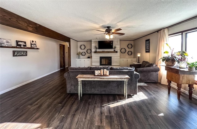 living room featuring a ceiling fan, a textured ceiling, wood finished floors, a fireplace, and baseboards