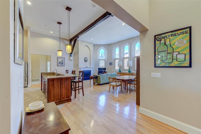 kitchen featuring light wood finished floors, baseboards, open floor plan, a breakfast bar area, and a kitchen island with sink