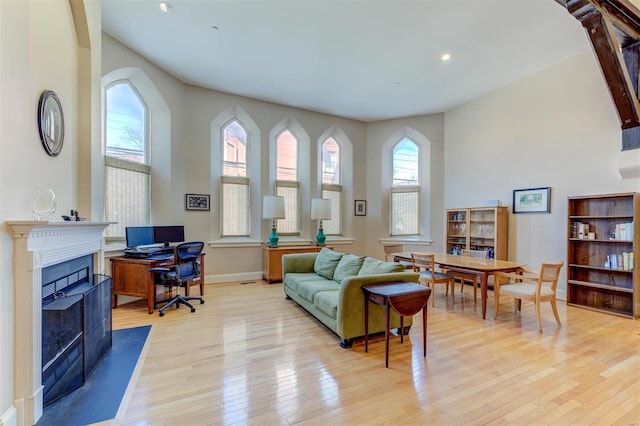 living room with recessed lighting, light wood-type flooring, baseboards, and a fireplace