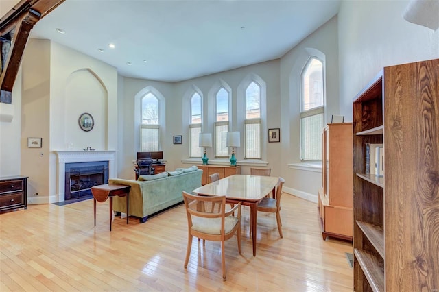 dining room with a fireplace with flush hearth, plenty of natural light, baseboards, and light wood-style floors