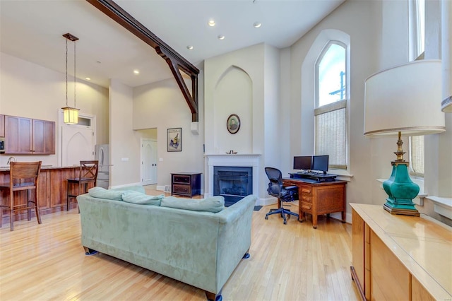 living room featuring recessed lighting, light wood-style floors, and a towering ceiling