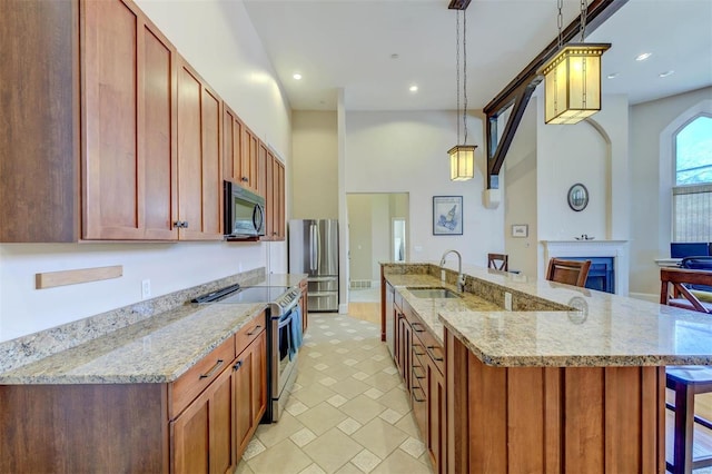 kitchen featuring a sink, recessed lighting, stainless steel appliances, light stone countertops, and hanging light fixtures