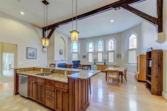 kitchen featuring brown cabinetry, light wood-style flooring, a sink, pendant lighting, and dishwasher