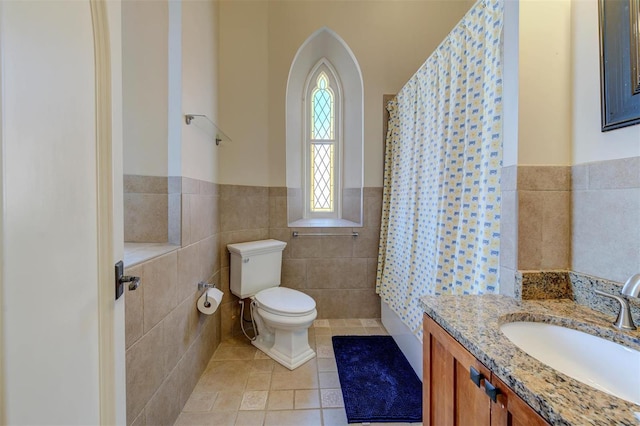 full bath with tile walls, a wainscoted wall, toilet, tile patterned floors, and vanity