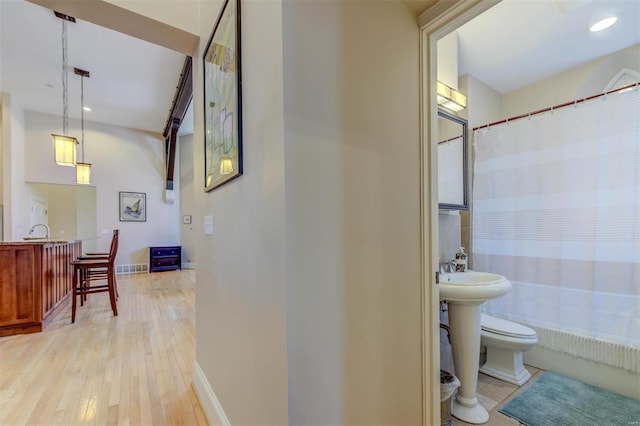 bathroom featuring a sink, baseboards, toilet, and wood finished floors