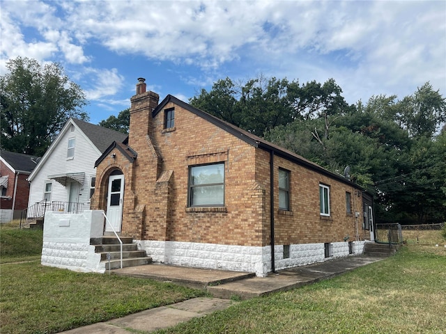 view of front of property with brick siding, a chimney, and a front lawn