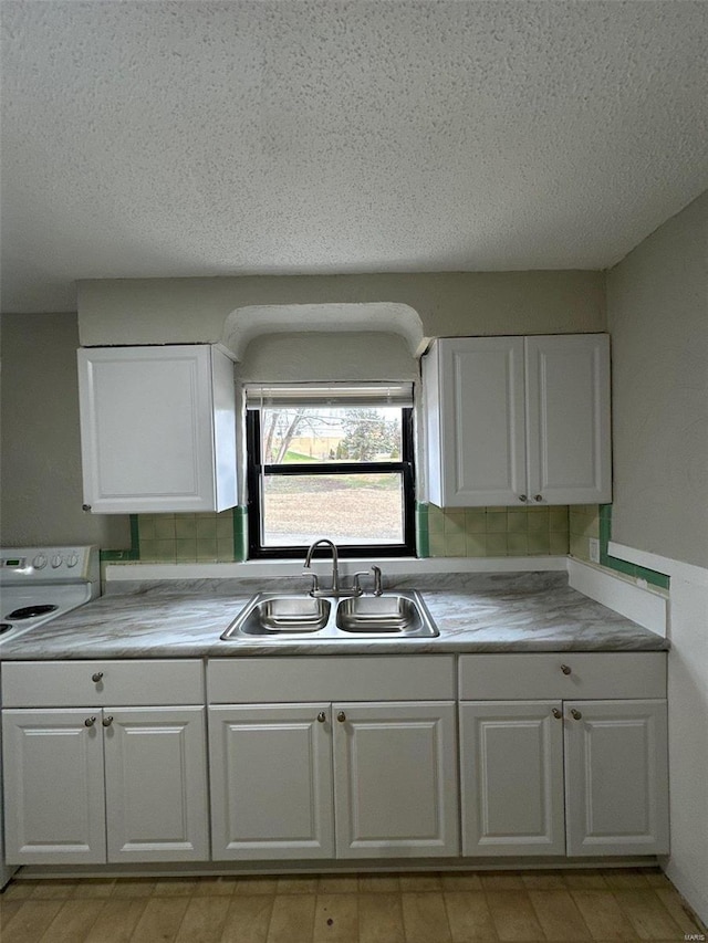 kitchen with a sink, light countertops, white cabinetry, and range with electric cooktop