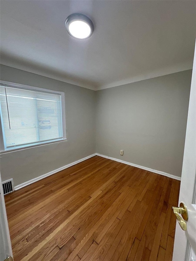 spare room featuring visible vents, wood-type flooring, and baseboards