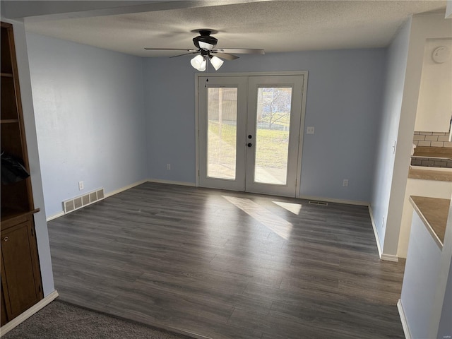 unfurnished living room featuring visible vents, dark wood-type flooring, a textured ceiling, french doors, and baseboards