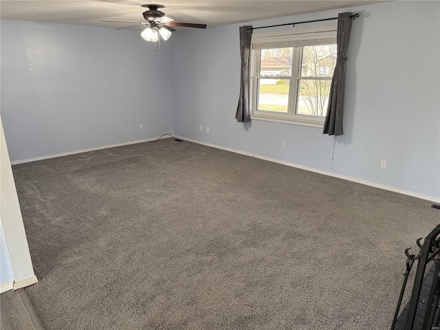 spare room featuring dark colored carpet, baseboards, and ceiling fan