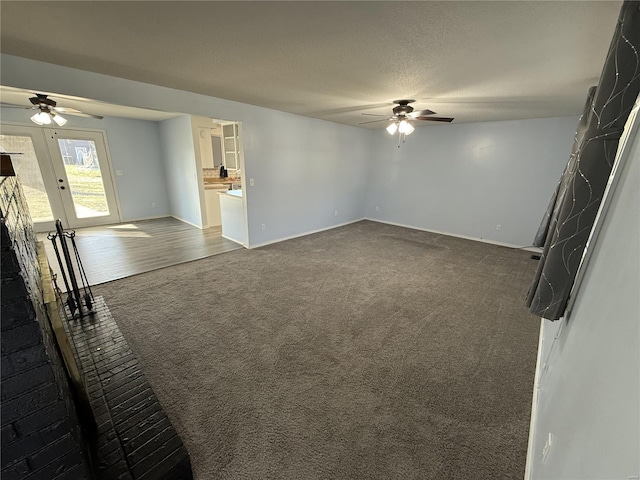 unfurnished living room featuring a ceiling fan, carpet, and a textured ceiling