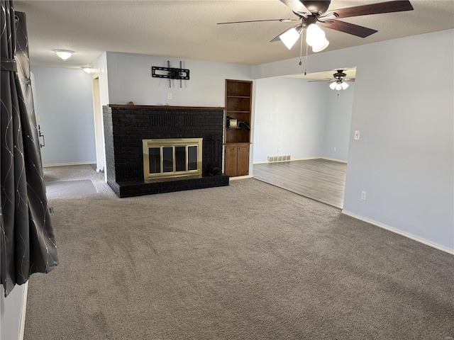 unfurnished living room with visible vents, a brick fireplace, baseboards, carpet, and a textured ceiling