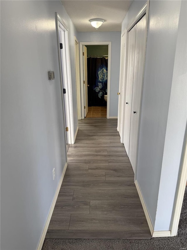 hall featuring baseboards and dark wood-style flooring