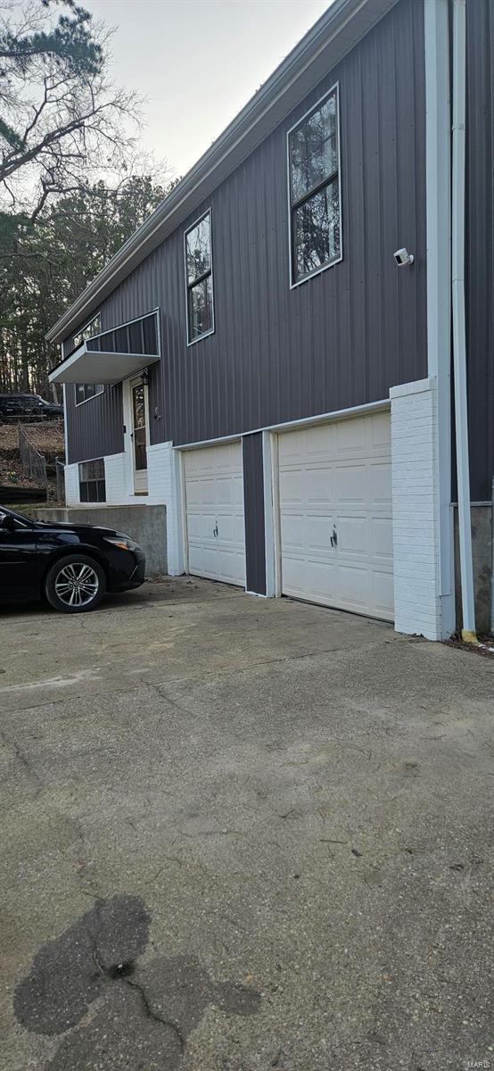 view of side of property with brick siding, an attached garage, and aphalt driveway