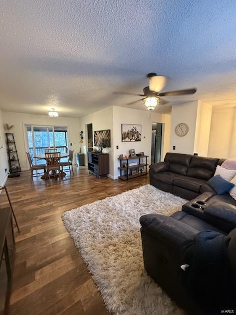 living room with ceiling fan, a textured ceiling, and wood finished floors