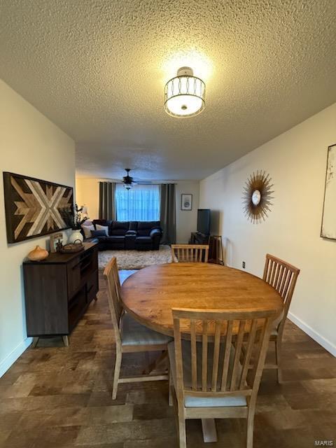 dining space featuring ceiling fan, baseboards, and a textured ceiling