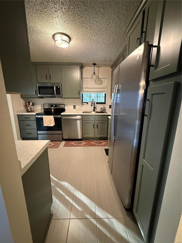 kitchen featuring a sink, light countertops, a textured ceiling, and stainless steel appliances