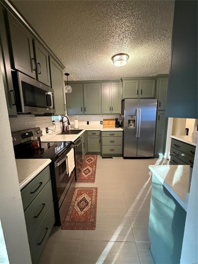 kitchen featuring appliances with stainless steel finishes, light countertops, and a sink