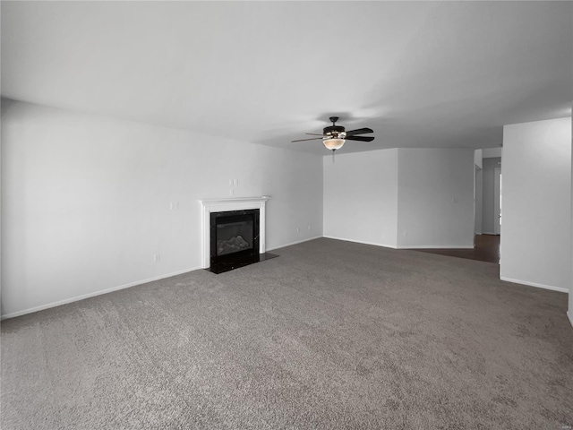 unfurnished living room featuring a fireplace with flush hearth, a ceiling fan, baseboards, and carpet floors