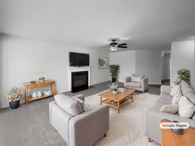 living room with light carpet, a fireplace with flush hearth, baseboards, and a ceiling fan