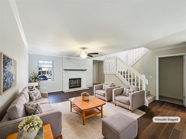 living room with a large fireplace, dark wood-type flooring, crown molding, stairs, and a textured ceiling