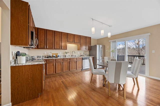 kitchen featuring a sink, light wood-style floors, appliances with stainless steel finishes, and pendant lighting