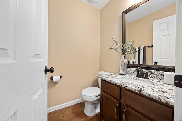 bathroom featuring vanity, toilet, wood finished floors, and baseboards