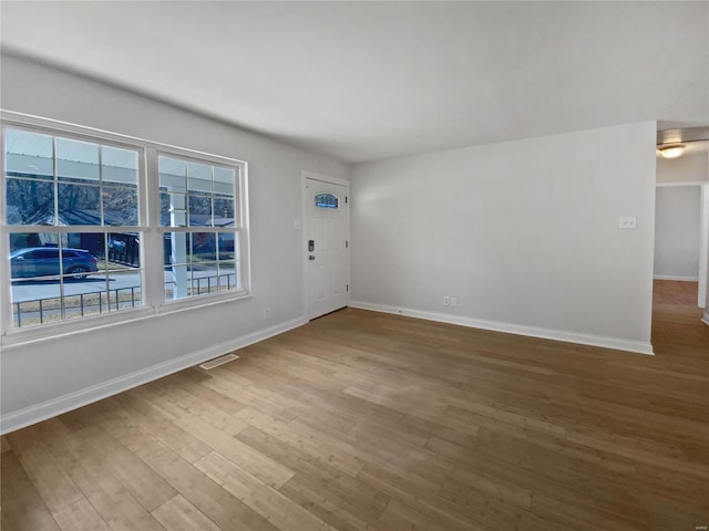 spare room with visible vents, baseboards, and wood finished floors